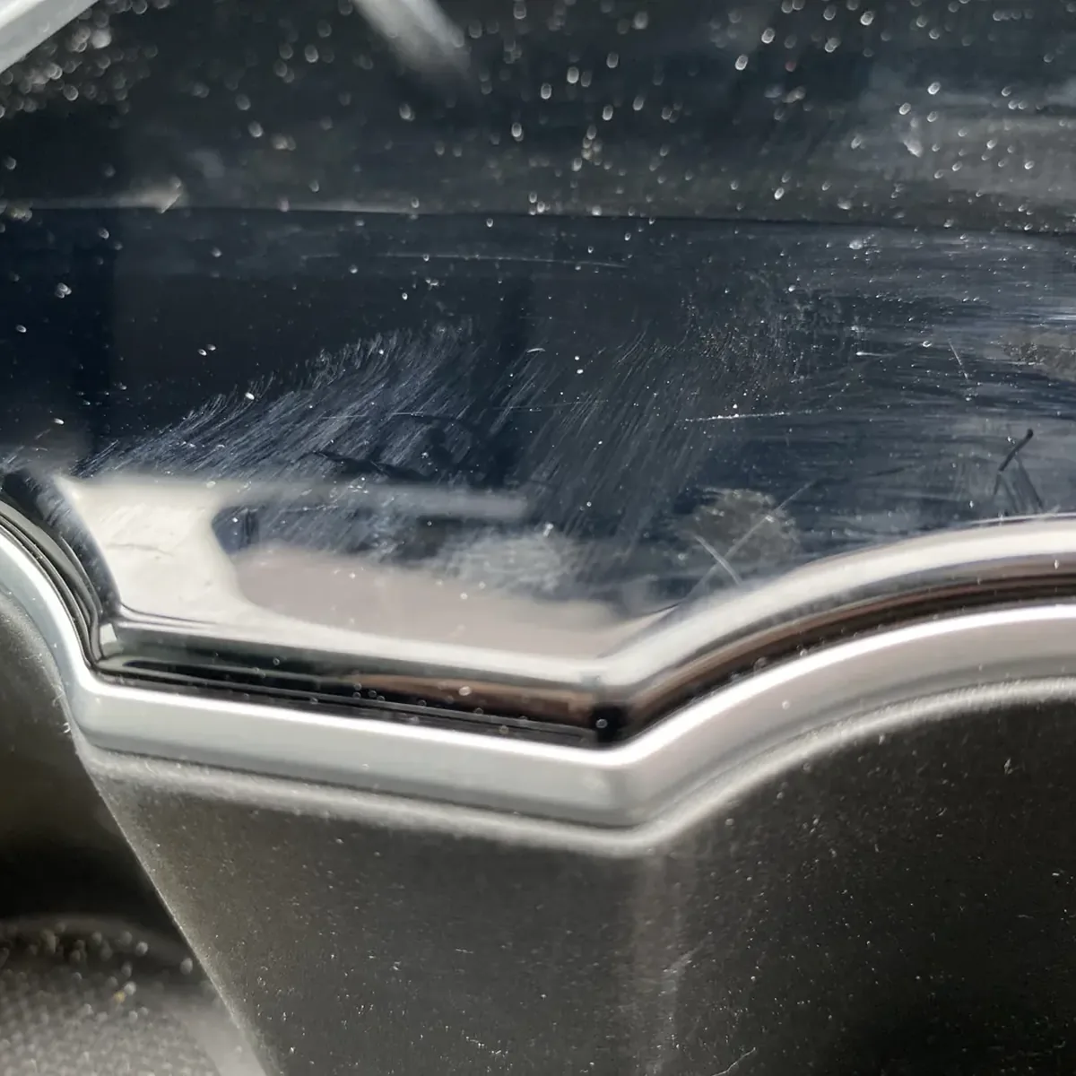The piano-black centre console of a Tesla Model 3, covered in scratches and dust